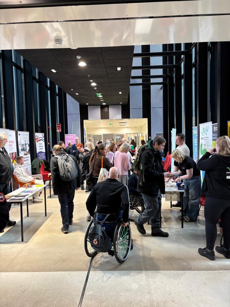 Kuva, jossa on isossa tilassa messustandeja ja ihmisiä tutustumassa niihin.